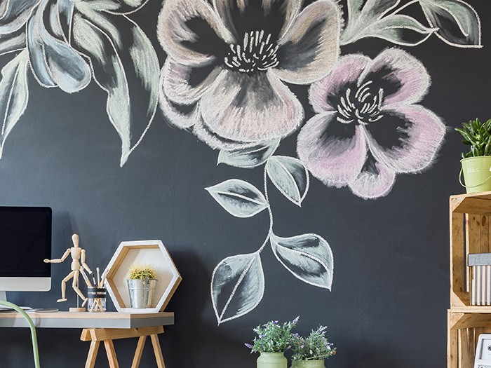 Black chalkboard wall featuring a colorful floral chalk design set behind a desk and bookshelves.